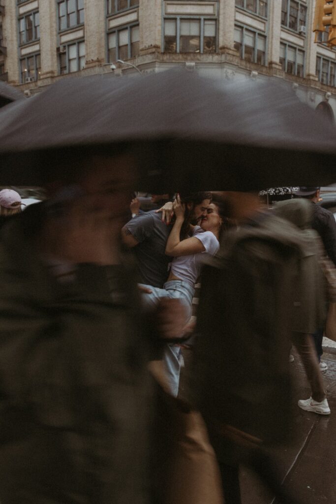 A photo of an embracing couple, seen through the blur of people moving through the foreground of the photo.